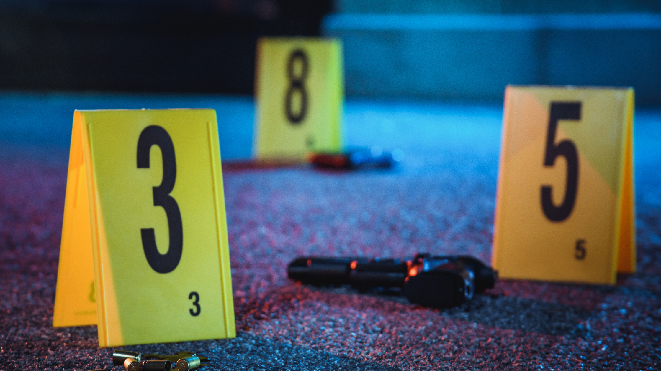 Crime scene numbers next to a pile of bullet casings, a glock, and another weapon.