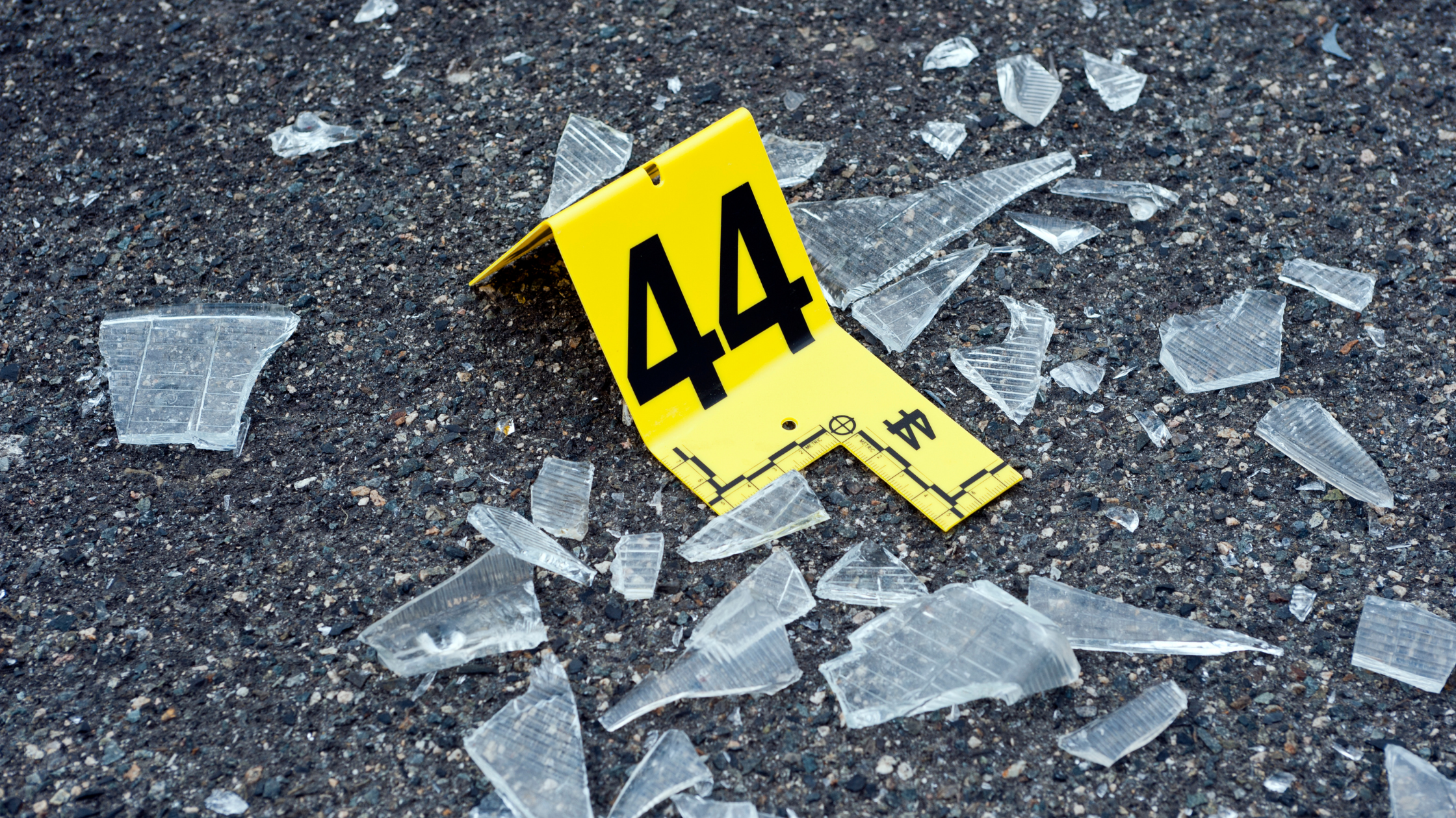 Shattered glass marked with a crime scene trace evidence examiner.